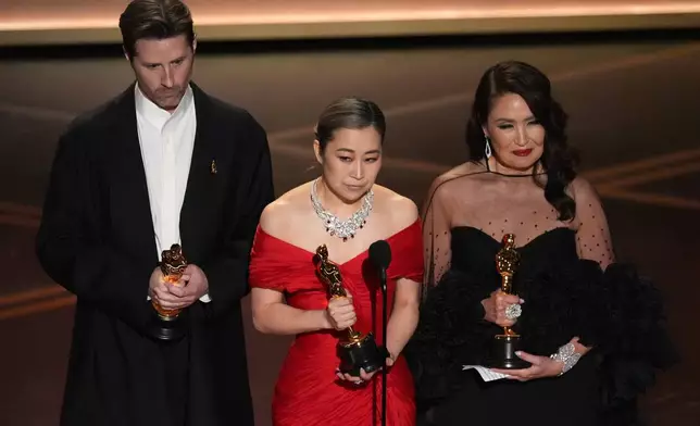 Chris Appelhans, from left, Maggie Kang, and Michelle L.M. Wong accept the award for animated feature film for "K-pop Demon Hunters" during the Oscars on Sunday, March 15, 2026, at the Dolby Theatre in Los Angeles. (AP Photo/Chris Pizzello)