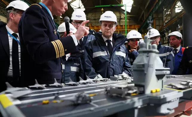 French President Emmanuel Macron, center, stands next to the model of a ship named "France Libre", during his visit to the construction site of Naval Group Nantes-Indret, where the next generation of French aircraft carrier is under construction, in Indret, France, Wednesday, March 18, 2026. (Gonzalo Fuentes/Pool Photo via AP)