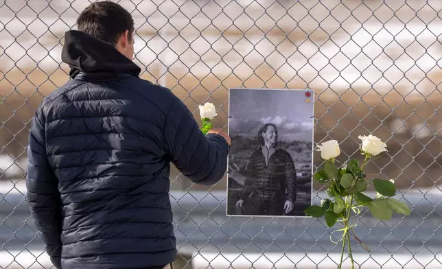 A man places a white rose on the memorial for Air Canada Jazz pilot Antoine Forest, who perished when his plane collided with an emergency vehicle at New York's LaGuardia Airport, in Montreal, Wednesday, March 25, 2026. (Christinne Muschi/The Canadian Press via AP)