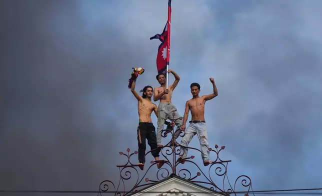 Protesters celebrate standing at the top of the Singha Durbar, the seat of Nepal's government's various ministries and offices, after it was set on fire during a protest against social media ban and corruption in Kathmandu, Nepal, Tuesday, Sept. 9, 2025. (AP Photo/Niranjan Shrestha, File)