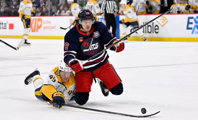 Nashville Predators' Reid Schaefer (49) reaches for the puck around Winnipeg Jets' Jacob Bryson (78) during the first period of their NHL hockey game in Winnipeg, Tuesday March 17, 2026. (Fred Greenslade/The Canadian Press via AP)