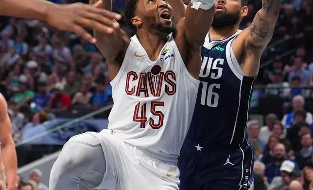 Cleveland Cavaliers guard Donovan Mitchell (45) goes up for a basket against Dallas Mavericks forward Caleb Martin (16) during the second half of an NBA basketball game Friday, March 13, 2026, in Dallas. (AP Photo/Julio Cortez)