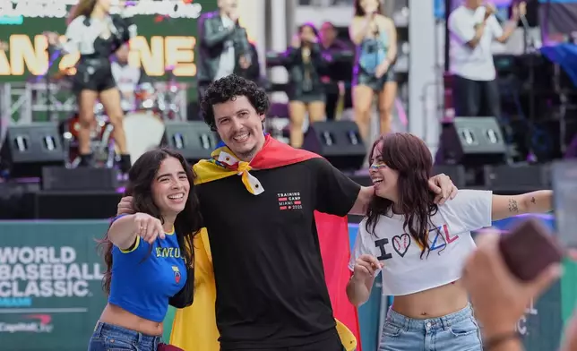 Venezuela fans pose for photos before the championship game of the World Baseball Classic against the United States, Tuesday, March 17, 2026, in Miami. (AP Photo/Lynne Sladky)