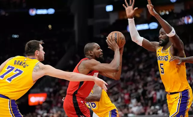 Houston Rockets' Kevin Durant, center shoots as Los Angeles Lakers' Luka Doncic (77) and Deandre Ayton (5) defend during the second half of an NBA basketball game Monday, March 16, 2026, in Houston. (AP Photo/David J. Phillip)