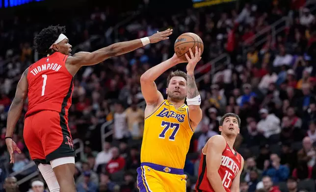 Los Angeles Lakers' Luka Doncic (77) shoots as Houston Rockets' Amen Thompson (1) defends during the first half of an NBA basketball game Monday, March 16, 2026, in Houston. (AP Photo/David J. Phillip)