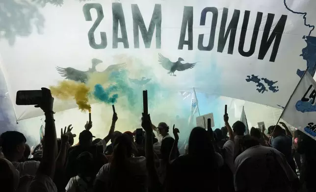 People rally with a banner reading in Spanish "Never again" on the anniversary of the military coup that brought the military regime to power, in Buenos Aires, Argentina, Tuesday, March 24, 2026. (AP Photo/Rodrigo Abd)