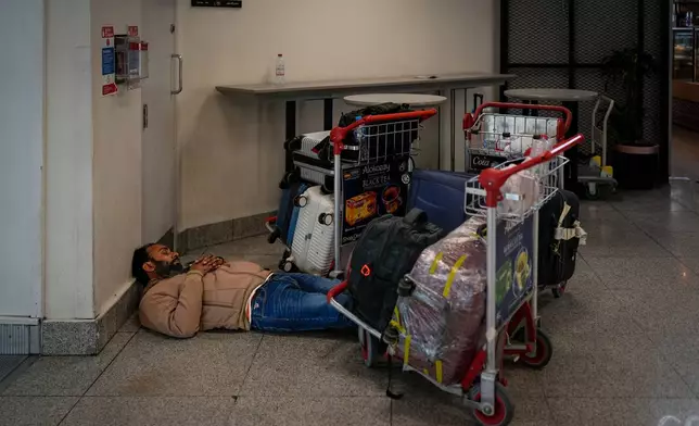 A stranded passenger sleeps on the floor outside Dubai International Airport terminal as the airport resumes limited operations in Dubai, United Arab Emirates, Thursday, March 5, 2026. (AP Photo/Altaf Qadri)