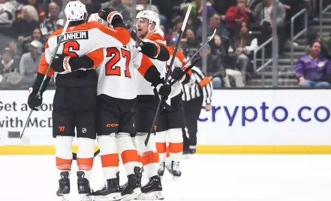 Philadelphia Flyers defenseman Travis Sanheim, left, celebrates with left wing Noah Cates (27) and defenseman Rasmus Ristolainen, right, after scoring a goal during the second period of an NHL hockey game against the Los Angeles Kings, Thursday, March 19, 2026, in Los Angeles. (AP Photo/Jessie Alcheh)
