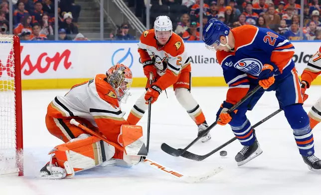 Anaheim Ducks goalie Lukas Dostal (1), Jackson LaCombe (2) and Edmonton Oilers' Curtis Lazar (20) scramble for the puck during the second period of an NHL hockey game in Edmonton, Alberta, Saturday March 28, 2026. (James Maclennan/The Canadian Press via AP)