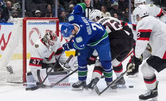 Vancouver Canucks' Nils Hoglander (21) looks for the puck after being stopped by Ottawa Senators goalie James Reimer (47) as Thomas Chabot (72) defends during the third period of an NHL hockey game, in Vancouver, on Monday, March 9, 2026. (Darryl Dyck/The Canadian Press via AP)
