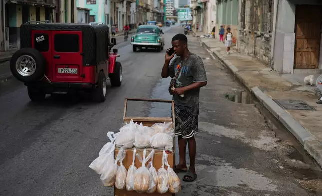 A bread vendor holds a cell phone up to his ear during irregular connectivity due to a blackout in Havana, Tuesday, March 17, 2026. (AP Photo/Ramon Espinosa)
