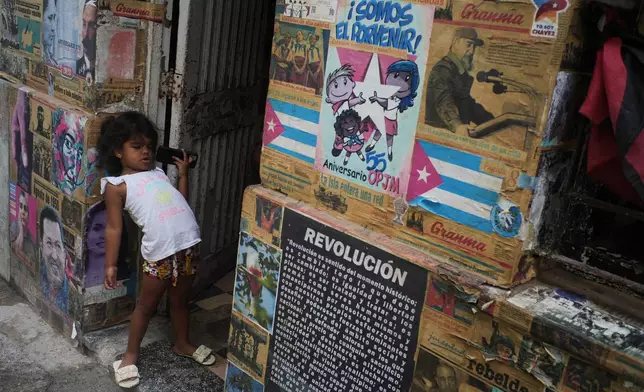 A girl plays in the doorway of the building where there is an art installation related to the Cuban Revolution, during a blackout in Havana, Tuesday, March 17, 2026. (AP Photo/Ramon Espinosa)