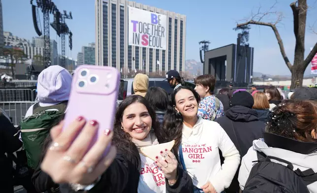 Fans of K-pop band BTS, Taylis Fahel, left, and Daniele Favero, right, from Brazil, take a selfie near a stage for the comeback concert of K-pop band BTS at Gwanghwamun Square in Seoul, South Korea, Saturday, March 21, 2026. (AP Photo/Lee Jin-man)
