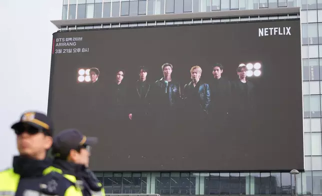 South Korean police officers stand near a billboard showing K-pop band BTS in Seoul, South Korea, Wednesday, March 11, 2026. (AP Photo/Lee Jin-man)