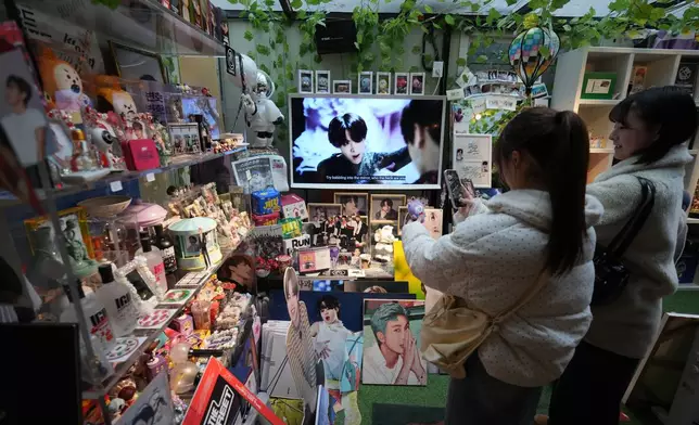 Fans of K-pop band BTS stand look at photos of BTS members at a cafe in Seoul, South Korea, Tuesday, March 17, 2026. (AP Photo/Lee Jin-man)