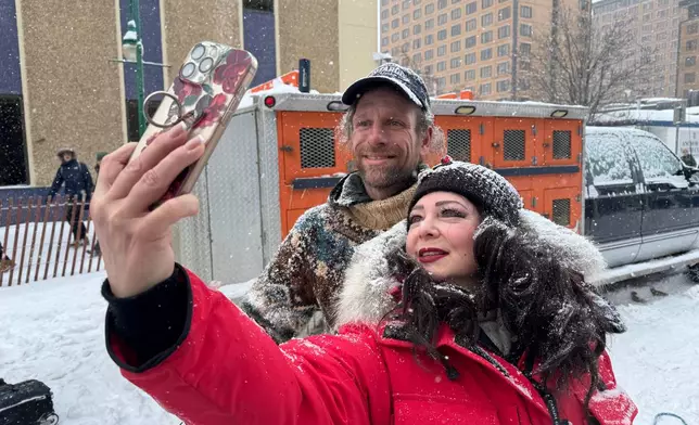 Defending Iditarod Trail Sled Dog Race champion Jessie Holmes poses for a selfie with a fan during the ceremonial start of this year's race in downtown Anchorage, Alaska, on Saturday, March 7, 2026. (AP Photo/Mark Thiessen)