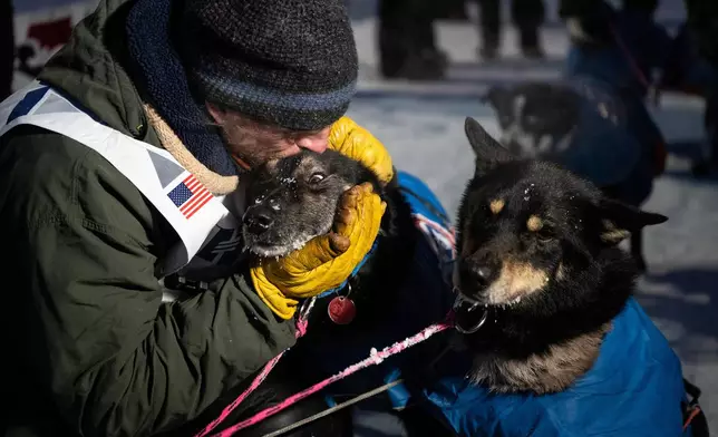 Jessie Holmes hugs his dogs at the finish line, after claiming his second straight Iditarod Trail Sled Dog Race championship, in Nome, Alaska, Tuesday March 17, 2026. (Marc Lester/Anchorage Daily News via AP)