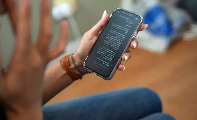 A Palestinian woman who traveled to South Africa via a charter flight organized by an Israeli group whose founder supported U.S. President Donald Trump's proposal to resettle Palestinians from Gaza, checks her phone in her temporary flat in Johannesburg, South Africa, Wednesday, Feb. 4, 2026. (AP Photo/Jerome Delay)