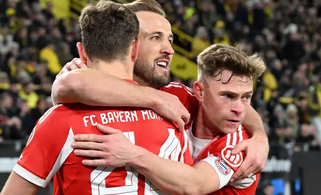 Bayern Munich's Harry Kane, center, celebrates scoring with Josip Stanisic and Joshua Kimmich, right, during the Bundesliga soccer match between Borussia Dortmund and FC Bayern Munich in Dortmund, Germany, Saturday Feb. 28, 2026. (Federico Gambarini/dpa via AP)
