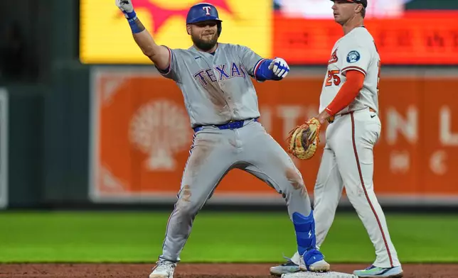 Texas Rangers' Jake Burger, left, celebrates after hitting a double during the ninth inning of a baseball game against the Baltimore Orioles, Monday, March 30, 2026, in Baltimore. (AP Photo/Stephanie Scarbrough)