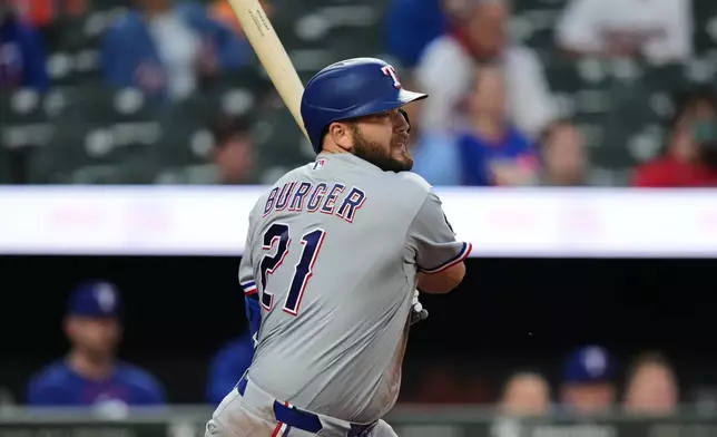 Texas Rangers' Jake Burger (21) follows through on an RBI single during the second inning of a baseball game against the Baltimore Orioles, Monday, March 30, 2026, in Baltimore. (AP Photo/Stephanie Scarbrough)