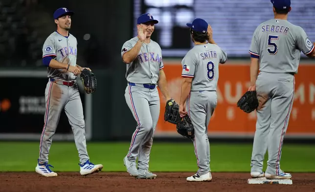 From left, Texas Rangers center fielder Evan Carter, left fielder Wyatt Langford, second baseman Josh Smith (8) and shortstop Corey Seager (5) celebrate their team's victory over the Baltimore Orioles in a baseball game, Monday, March 30, 2026, in Baltimore. (AP Photo/Stephanie Scarbrough)