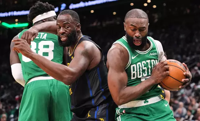 Boston Celtics guard Jaylen Brown, right, grabs a rebound against Golden State Warriors forward Draymond Green (23) during the first half of an NBA basketball game, Wednesday, March 18, 2026, in Boston. (AP Photo/Charles Krupa)
