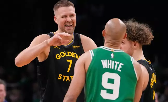 Golden State Warriors center Kristaps Porzingis (7) jokes with his former teammate Boston Celtics guard Derrick White (9) during the first half of an NBA basketball game, Wednesday, March 18, 2026, in Boston. (AP Photo/Charles Krupa)