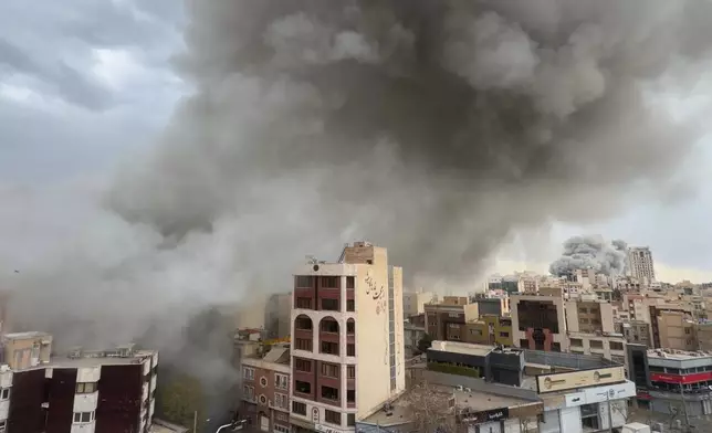 Plumes of smoke from two simultaneous strikes rise over Tehran, Iran, Monday, March 2, 2026. (AP Photo/Mohsen Ganji)