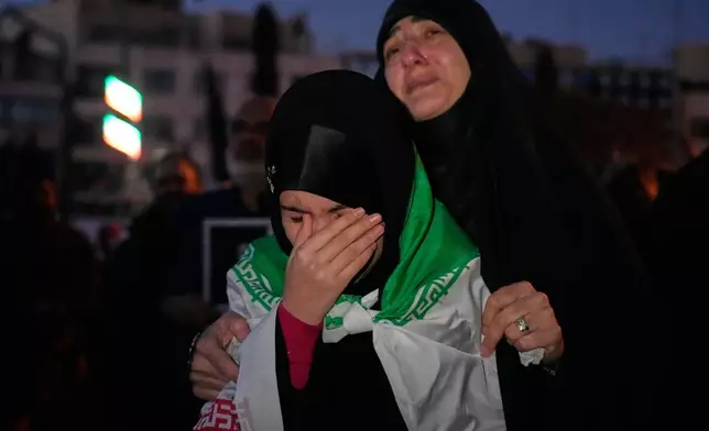 Government supporters mourn in a gathering after state TV officially announced the death of Iranian Supreme Leader Ayatollah Ali Khamenei, as one of them wears an Iranian flag, in Tehran, Iran, Sunday, March 1, 2026. (AP Photo/Vahid Salemi)