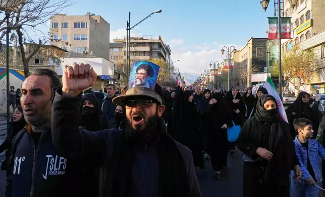 A man wearing a hat bearing a picture of the late Iranian Supreme Leader Ayatollah Ali Khamenei marches with a group of government supporters toward Khamenei's residency in Tehran, Iran, Sunday, March 1, 2026, following the confirmed death of Khamenei in U.S. and Israeli strikes. (AP Photo/Vahid Salemi)