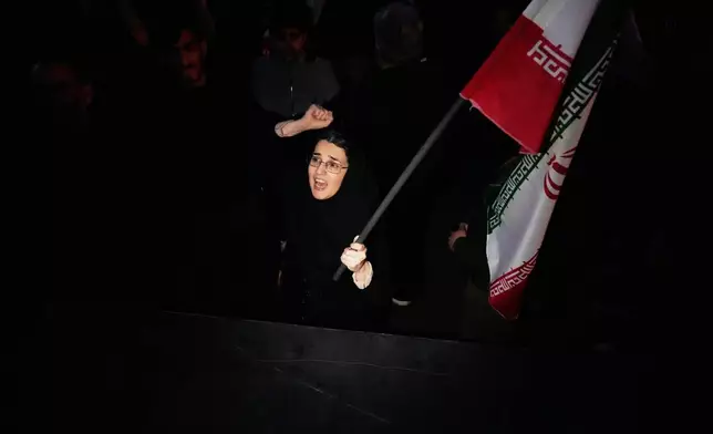 A government supporter chants slogan as she holds an Iranian flag while attending a mourning ceremony after state TV officially announced the death of Iranian Supreme Leader Ayatollah Ali Khamenei, in Tehran, Iran, Sunday, March 1, 2026. (AP Photo/Vahid Salemi)