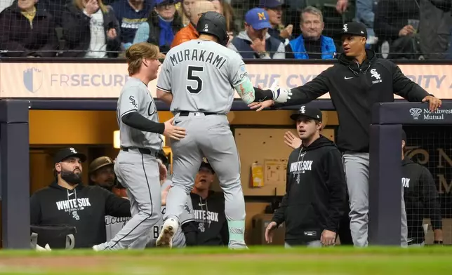 Chicago White Sox's Chase Meidroth, left, and manager Will Venable, right, congratulate Munetaka Murakami (5) after Murakami hit a home run during the fourth inning of a baseball game against the Milwaukee Brewers, Saturday, March 28, 2026, in Milwaukee. (AP Photo/Kayla Wolf)