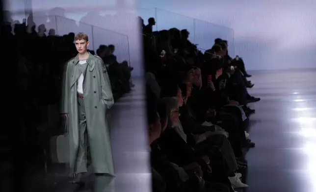 A model, reflected in glass, wears a creation from the Giorgio Armani Fall/Winter 2026-2027 Women's collection presented in Milan, Italy, Sunday, March 1, 2026. (AP Photo/Antonio Calanni)
