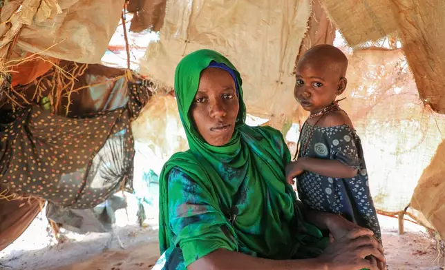 Nurto Madey, a mother displaced by drought, holds her daughter inside her makeshift hut at Ladan internally displaced persons (IDP) camp in Dolow, southern Somalia, Wednesday, March 25, 2026. (AP Photo/Mohamed Sheikh Nor)