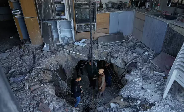 Residents inspect damage which according to them was caused by fragments of an intercepted Iranian rocket that landed on a Palestinian three story building, in West Bank town of Biddya, west of Salfit, Wednesday, March 11, 2026. (AP Photo/Majdi Mohammed)