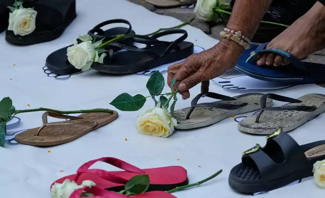 Families of victims of former Philippine President Rodrigo Duterte's "war on drugs" place a rose beside slippers during a ceremony at a church in Quezon City, Philippines, as they mark one year since the arrest of Duterte on Wednesday, March 11, 2026. (AP Photo/Aaron Favila)