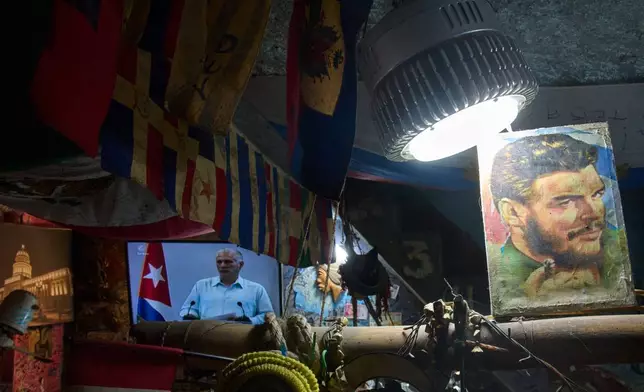 An image of Cuban Revolutionary hero Ernesto "Che" Guevara stands next to a TV showing Cuban President Miguel Diaz-Canel speaking, inside a souvenir shop in Havana, Cuba, Friday, March 13, 2026. (AP Photo/Ramon Espinosa)
