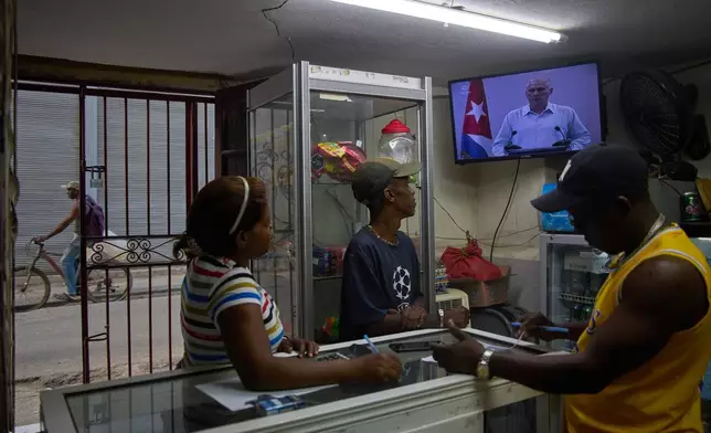 People inside a private convenience store see Cuban President Miguel Diaz-Canel speaking on TV in Havana, Cuba, Friday, March 13, 2026. (AP Photo/Ramon Espinosa)