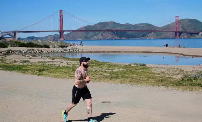 A man runs past at Crissy Field, backdropped by the Golden Gate Bridge in San Francisco, Tuesday, March 17, 2026. (AP Photo/Godofredo A. Vásquez)