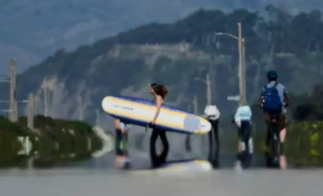 Heat waves from the road rise as people walk along The Great Highway in San Francisco, Tuesday, March 17, 2026. (AP Photo/Jeff Chiu)
