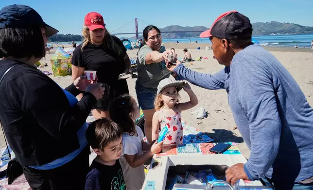 People buy ice cream treats from a paletero at Crissy Field East Beach in San Francisco, Tuesday, March 17, 2026. (AP Photo/Godofredo A. Vásquez)