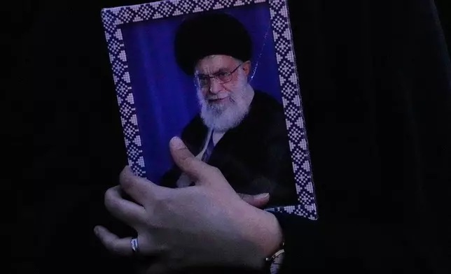 A government supporter holds a picture of the Iranian Supreme Leader Ayatollah Ali Khamenei during a gathering after state TV officially announced the death of Khamenei, in Tehran, Iran, Sunday, March 1, 2026. (AP Photo/Vahid Salemi)