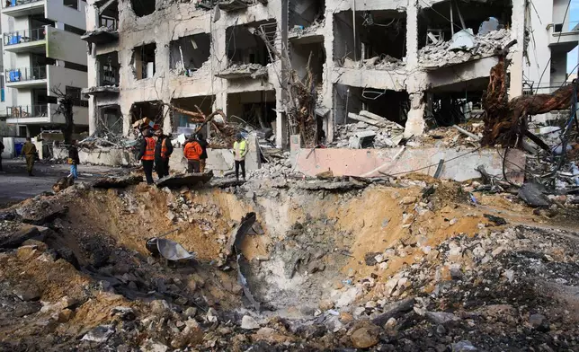 Rescue workers and military personnel survey the scene of a direct hit a day after an Iranian missile struck in Tel Aviv, Israel, Sunday, March 1, 2026. (AP Photo/Oded Balilty)