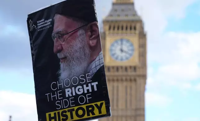 A protester holds a placard in London, Saturday, Feb. 28, 2026 after U.S. and Israeli forces carried out a series of strikes on Iran on Saturday morning. (AP Photo/Alastair Grant)