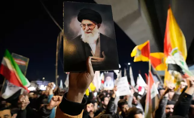 A protester holds a portrait of Iran's Supreme Leader Ayatollah Ali Khamenei during a protest against U.S. and Israeli attacks on multiple cities across Iran at a bridge leading to the fortified Green Zone where the U.S. embassy is located in Baghdad, Iraq, Saturday, Feb. 28, 2026. (AP Photo/Hadi Mizban)