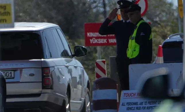 A police officer salutes as vehicles transport British Defence Secretary John Healey enter at the U.K.'s RAF Akrotiri air base near Limassol, Cyprus, Thursday, March 5, 2026. (AP Photo/Petros Karadjias)