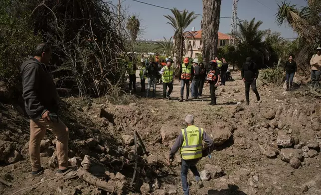 Residents and Israeli security forces inspect the site struck by an Iranian missile in central Israel, Thursday, March 5, 2026. (AP Photo/Leo Correa)