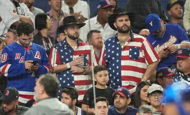 United State fans stand at the end of the championship game of the World Baseball Classic against Venezuela, Tuesday, March 17, 2026, in Miami. (AP Photo/Rebecca Blackwell)