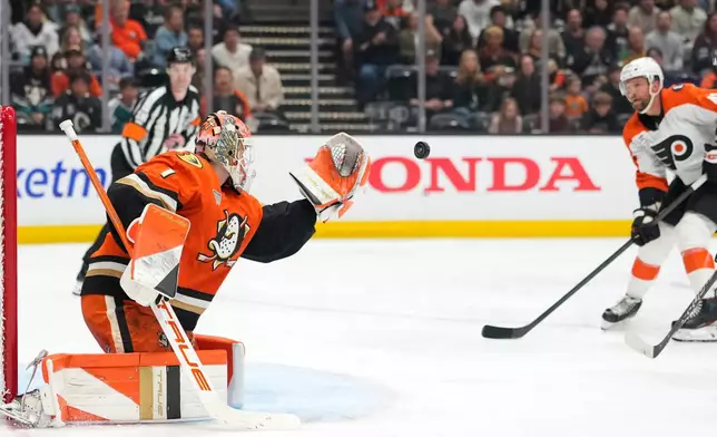 Anaheim Ducks goaltender Lukas Dostal, left, stops a shot as Philadelphia Flyers center Luke Glendening watches during the second period of an NHL hockey game Wednesday, March 18, 2026, in Anaheim, Calif. (AP Photo/Mark J. Terrill)